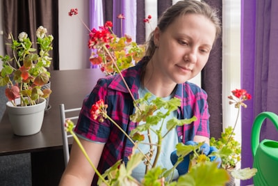 a woman sitting at a table in front of a potted plant