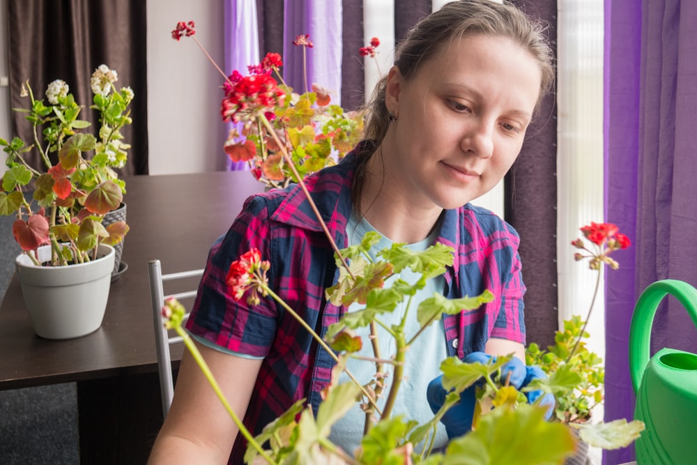 a woman sitting at a table in front of a potted plant