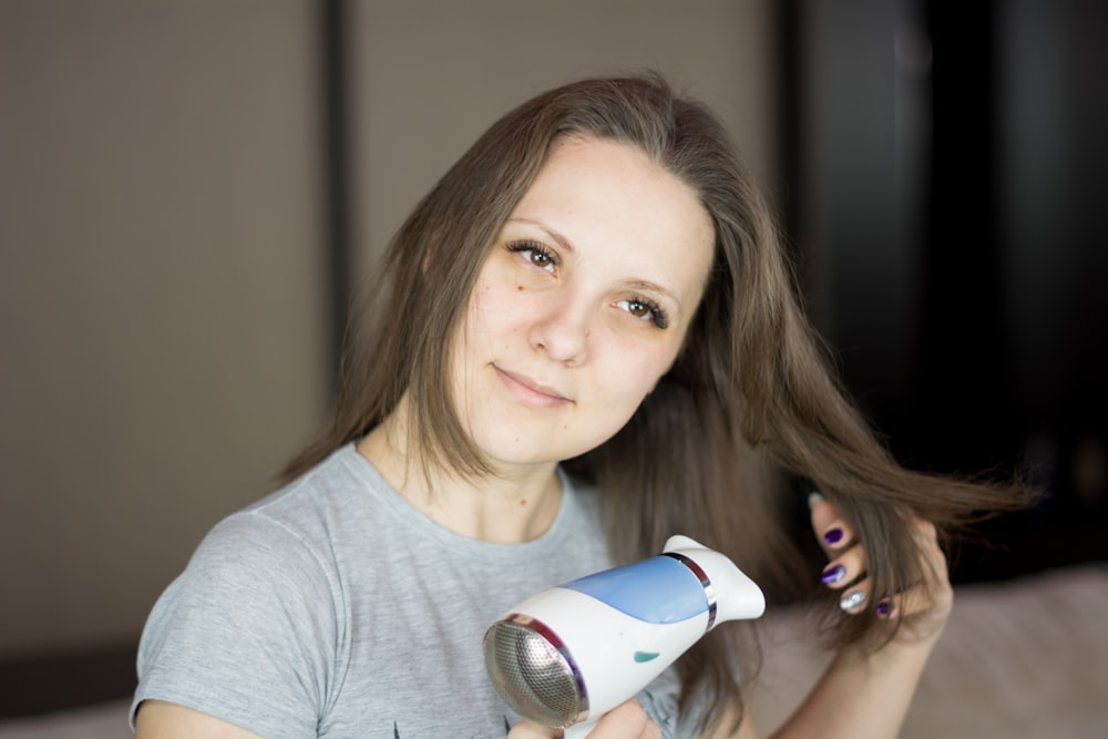 uma mulher secando o cabelo com um secador de cabelo