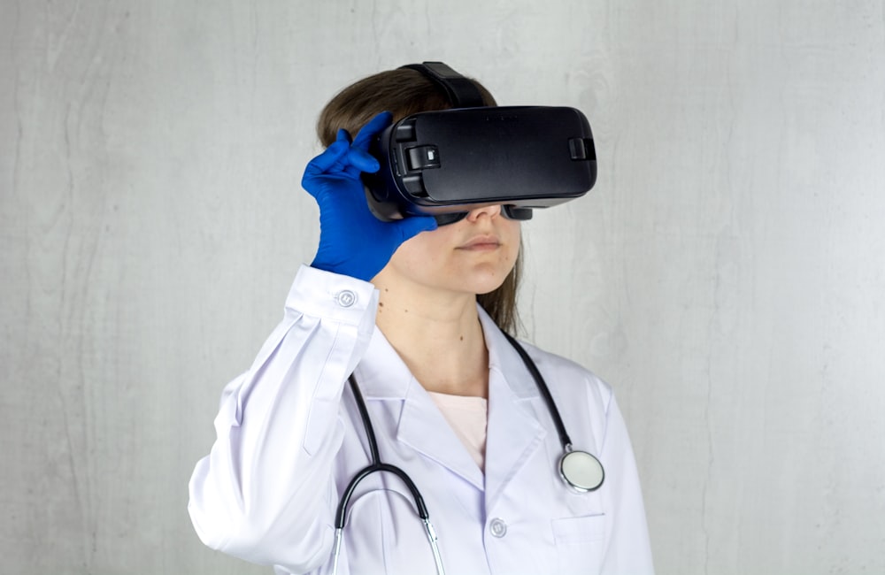 Eine Frau im weißen Kittel und blauen Handschuhen trägt ein virtuelles Headset