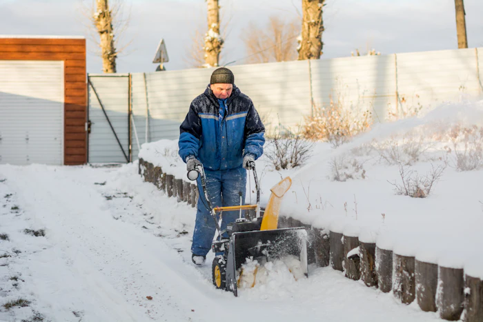 A worker clearing deep snow with a snow blower
