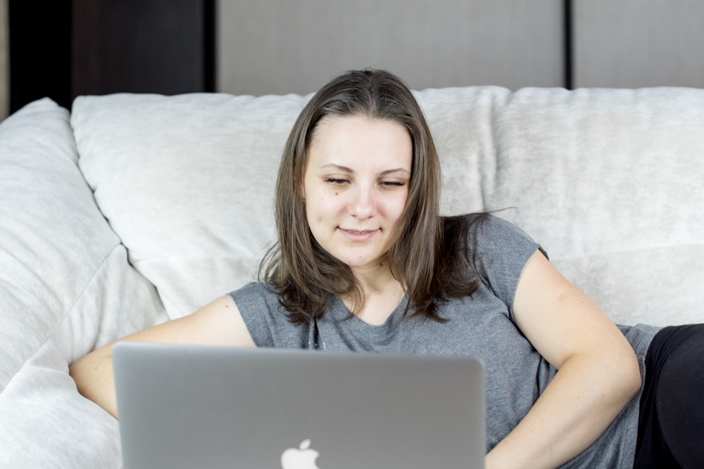 a woman sitting on a couch using a laptop computer