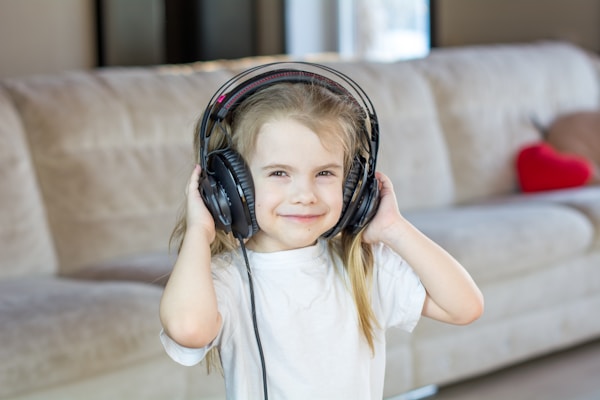 Enfant écoutant attentivement des podcasts avec un casque audio coloré