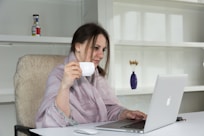 a woman sitting at a desk with a laptop and a cup of coffee