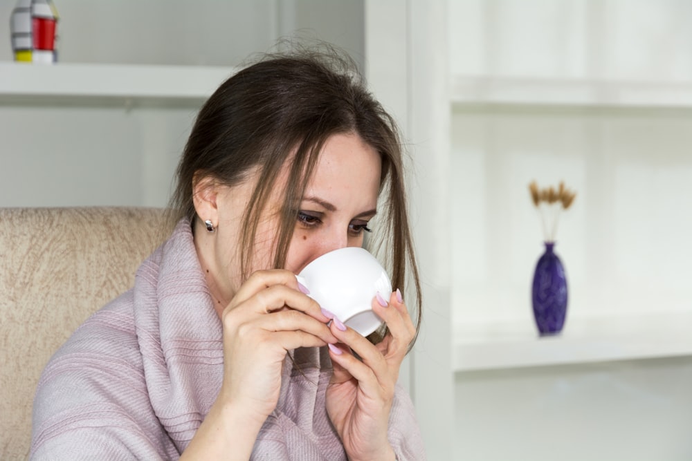 a woman sitting in a chair drinking from a cup