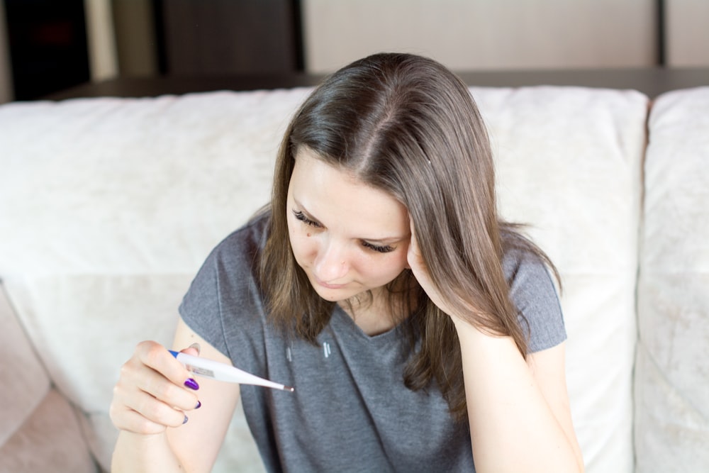 a woman sitting on a couch holding a pen and paper