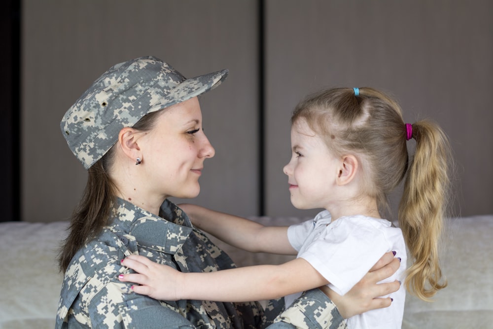 a woman in a military uniform hugging a little girl