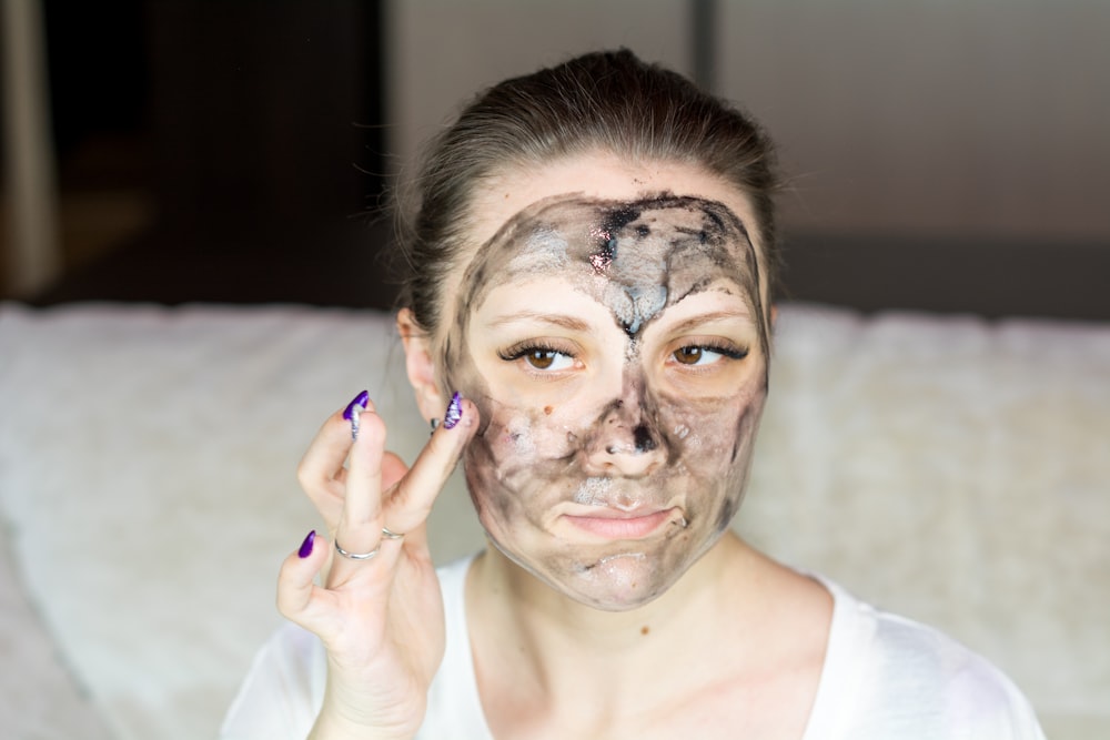 a woman with a face mask on holding her hand up to her face