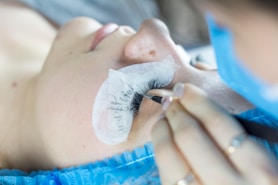 a woman getting her eyelashes done by a professional makeup artist
