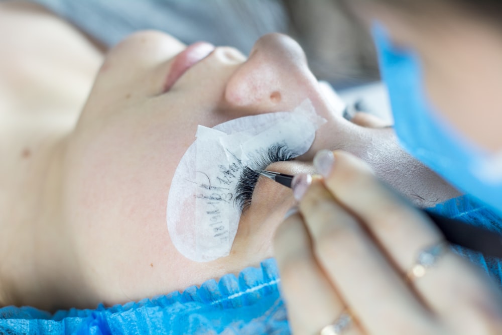 Eine Frau, die ihre Wimpern von einem professionellen Visagisten machen lässt