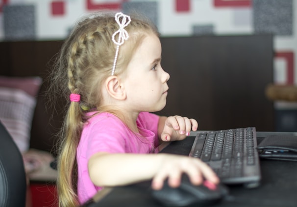 a little girl sitting in front of a computer keyboard