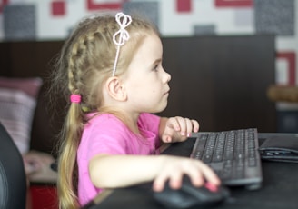 a little girl sitting in front of a computer keyboard