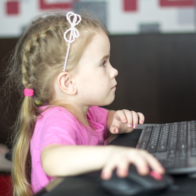 a little girl sitting in front of a computer keyboard