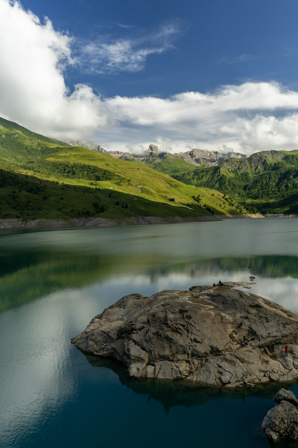 a large body of water surrounded by a lush green hillside