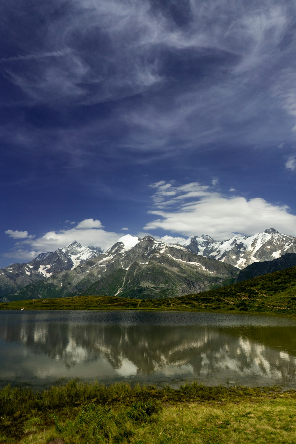 a lake surrounded by mountains under a cloudy sky