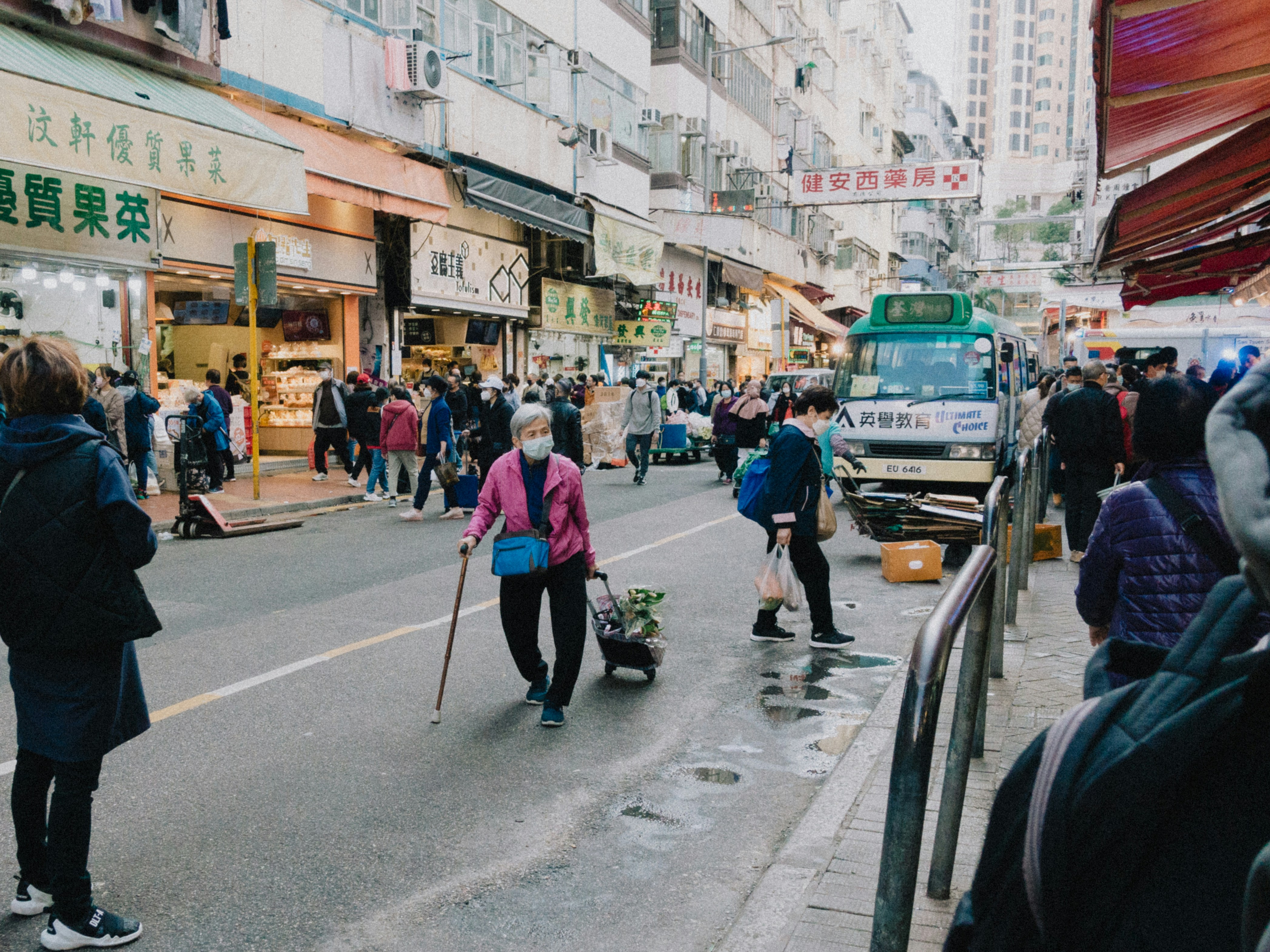 A group of people walking down a street next to tall buildings