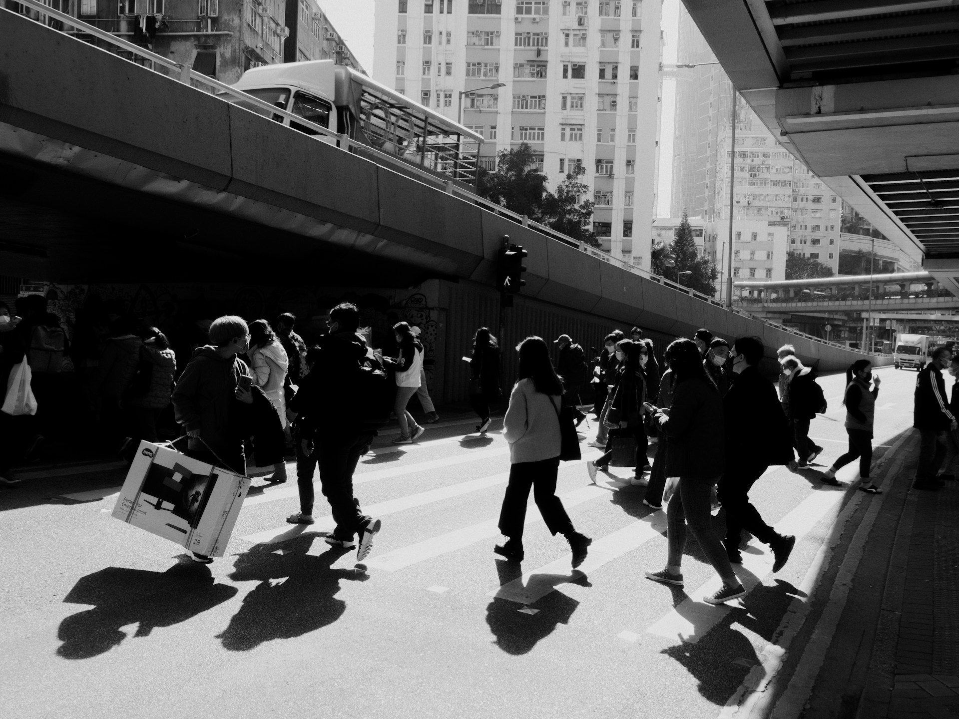 a group of people walking down a street next to tall buildings