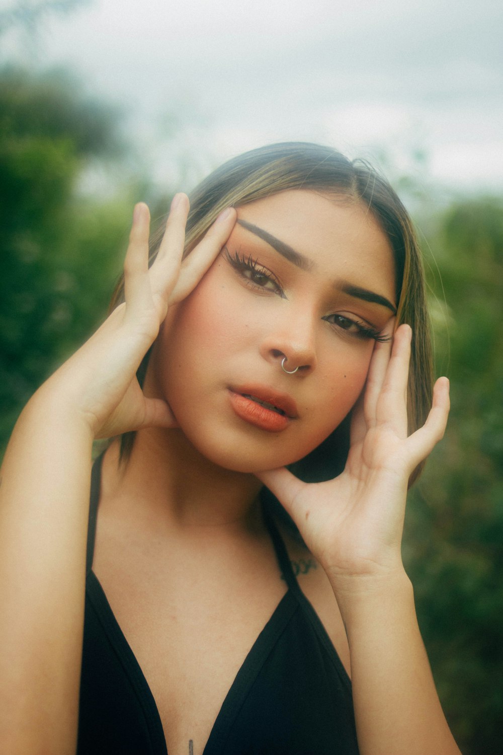 a woman in a black dress holding her hand to her face