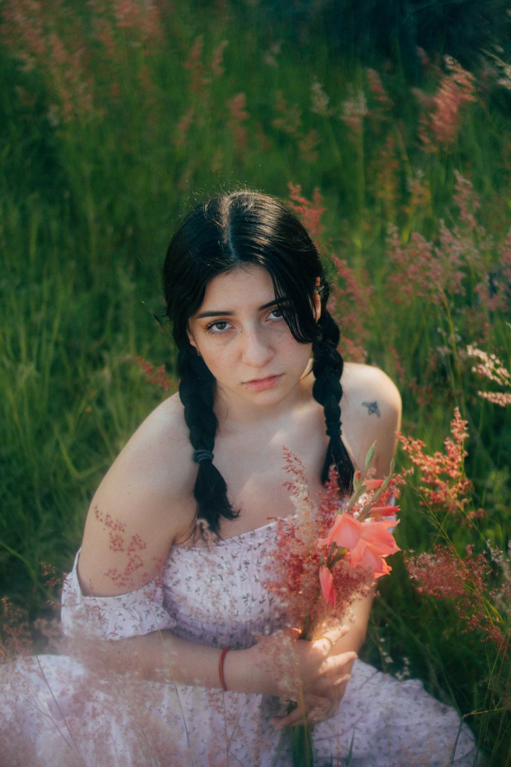 a woman in a dress sitting in a field of flowers