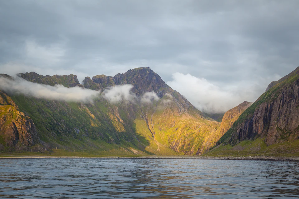 Serene mountainous landscape with lush green vegetation on a jagged mountain peak surrounded hills