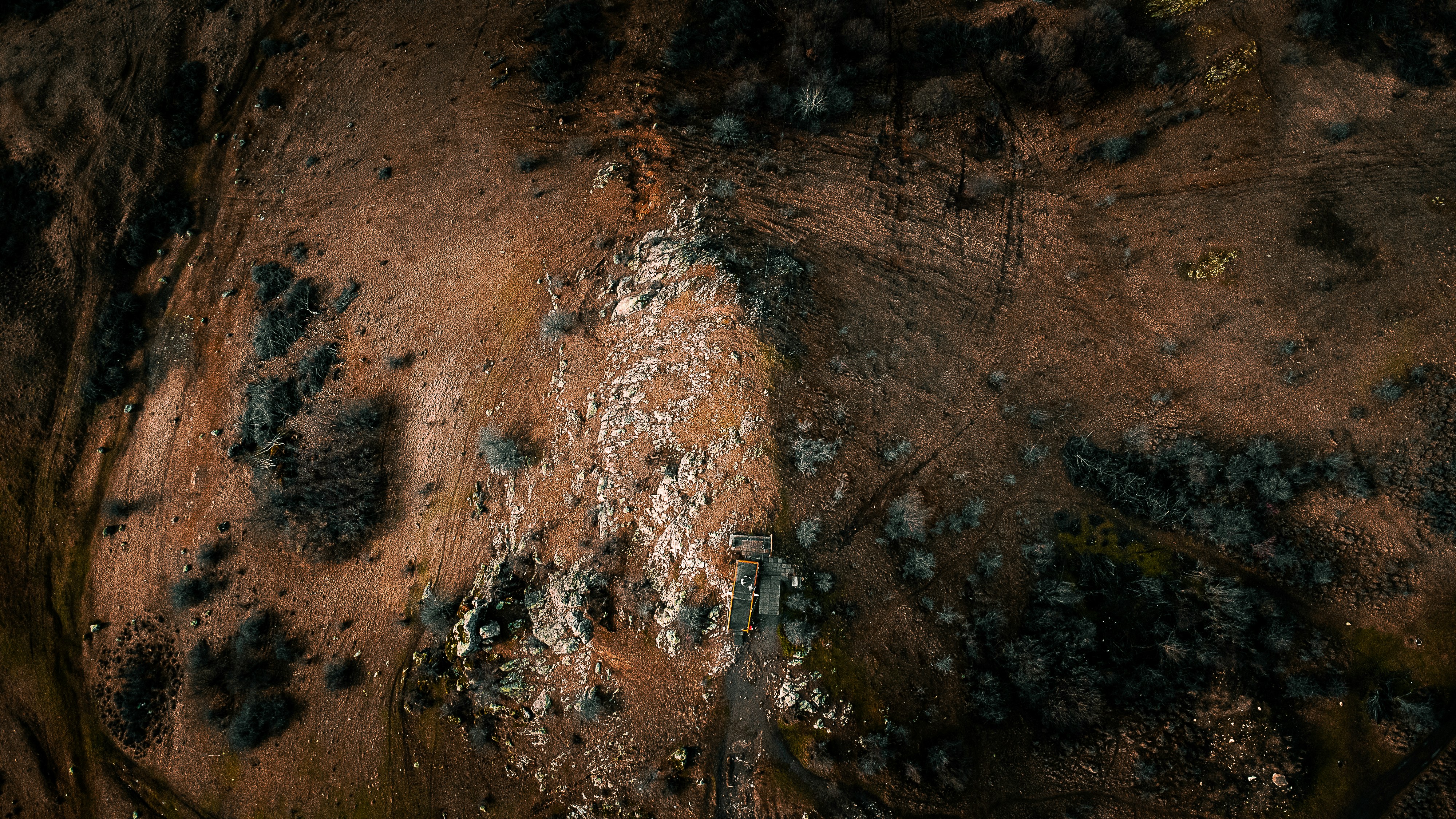 an aerial view of a dirt field with trees