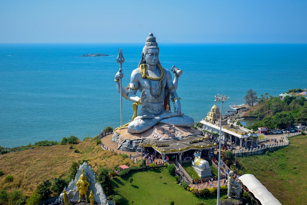 a large statue of a person sitting on top of a lush green field