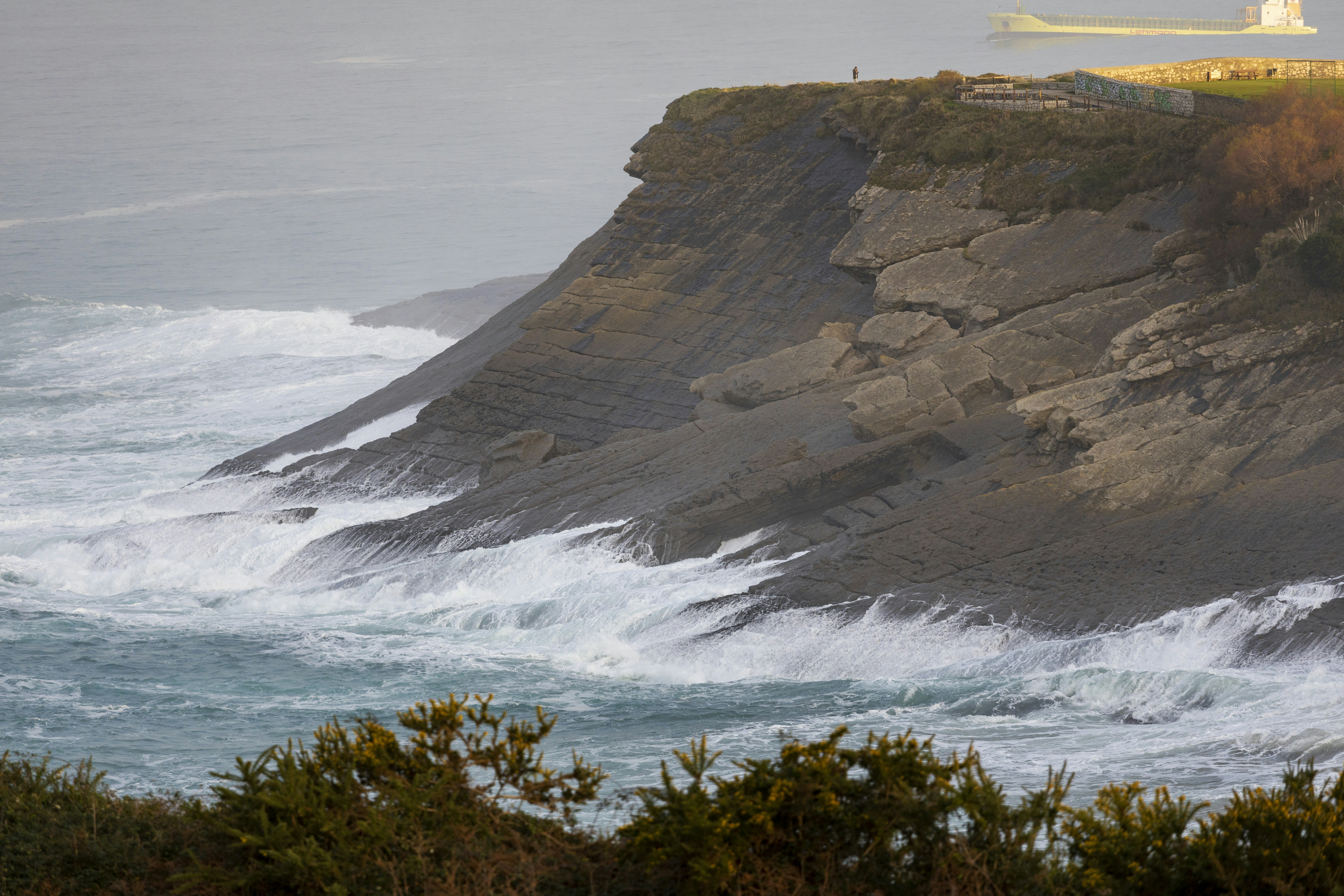 A lighthouse on a cliff overlooking the ocean photo – Free Cliff Image ...