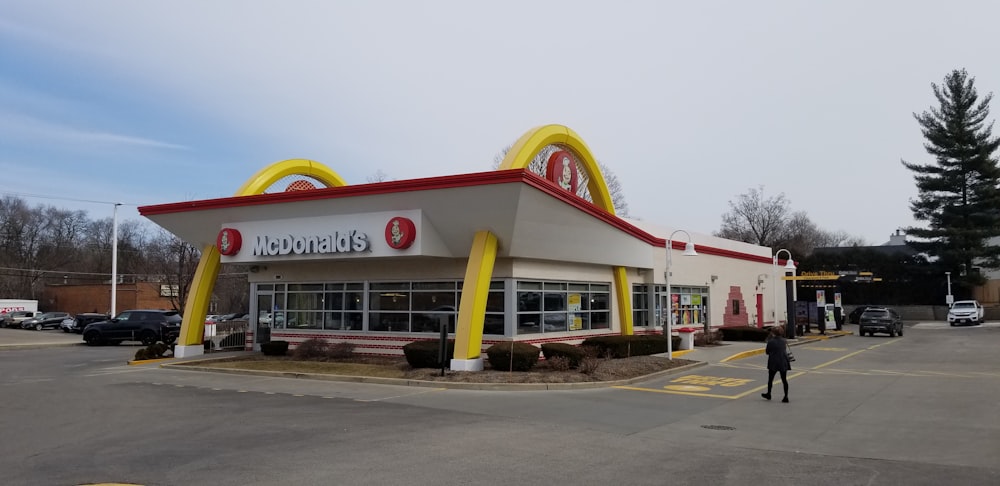 a mcdonald's restaurant with a man walking in front of it