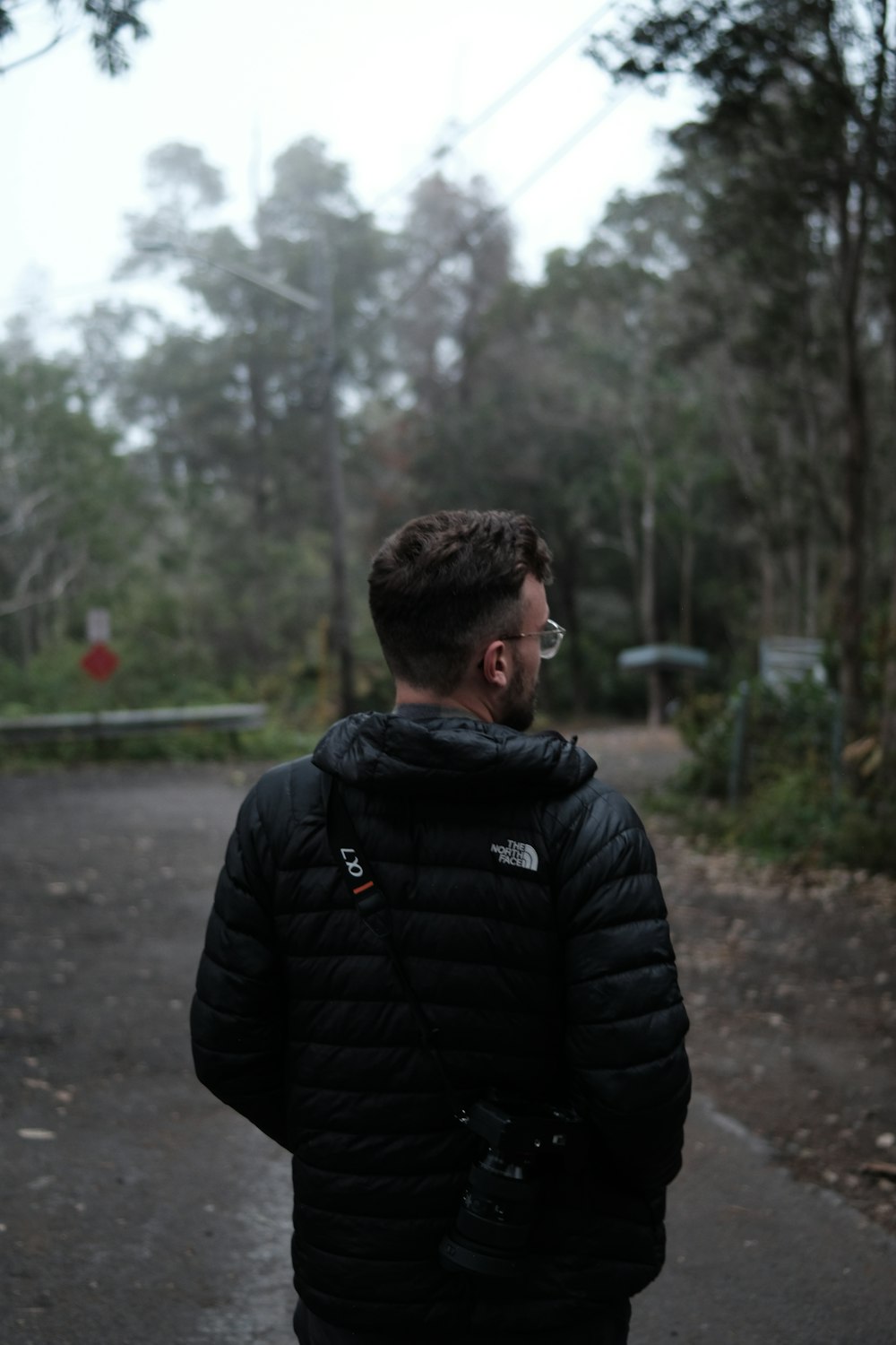 a man in a black jacket walking down a road