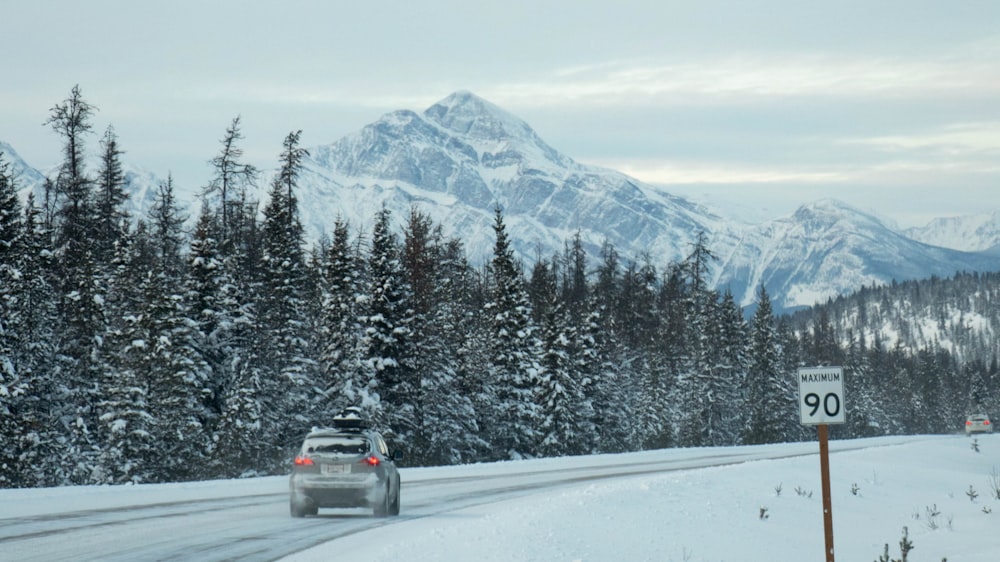 a car driving on a snowy road with mountains in the background