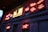 Neon signs are displayed on a building facade, primarily featuring red and yellow colors. The signs include text related to Scotland and various phrases in glowing neon script.