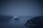 A large cruise ship navigates through a misty waterway surrounded by dark, forested cliffs. The scene is enveloped in fog, creating a mysterious and serene atmosphere.