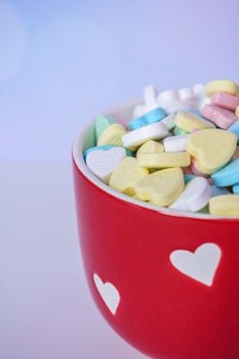 a red bowl filled with lots of candy hearts