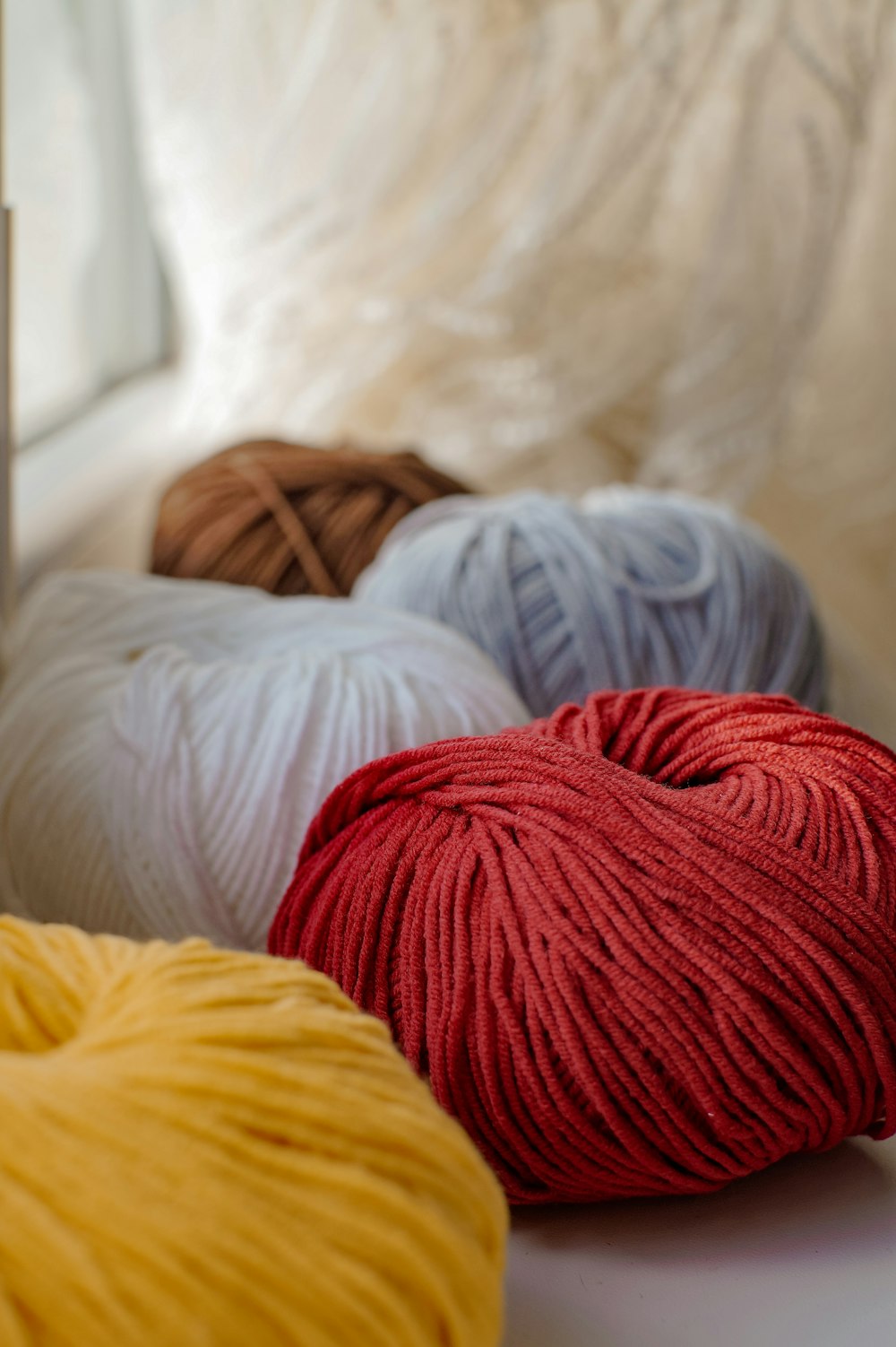 a row of balls of yarn sitting on a window sill