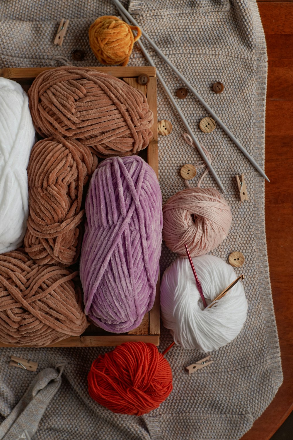 a wooden box filled with balls of yarn and knitting needles