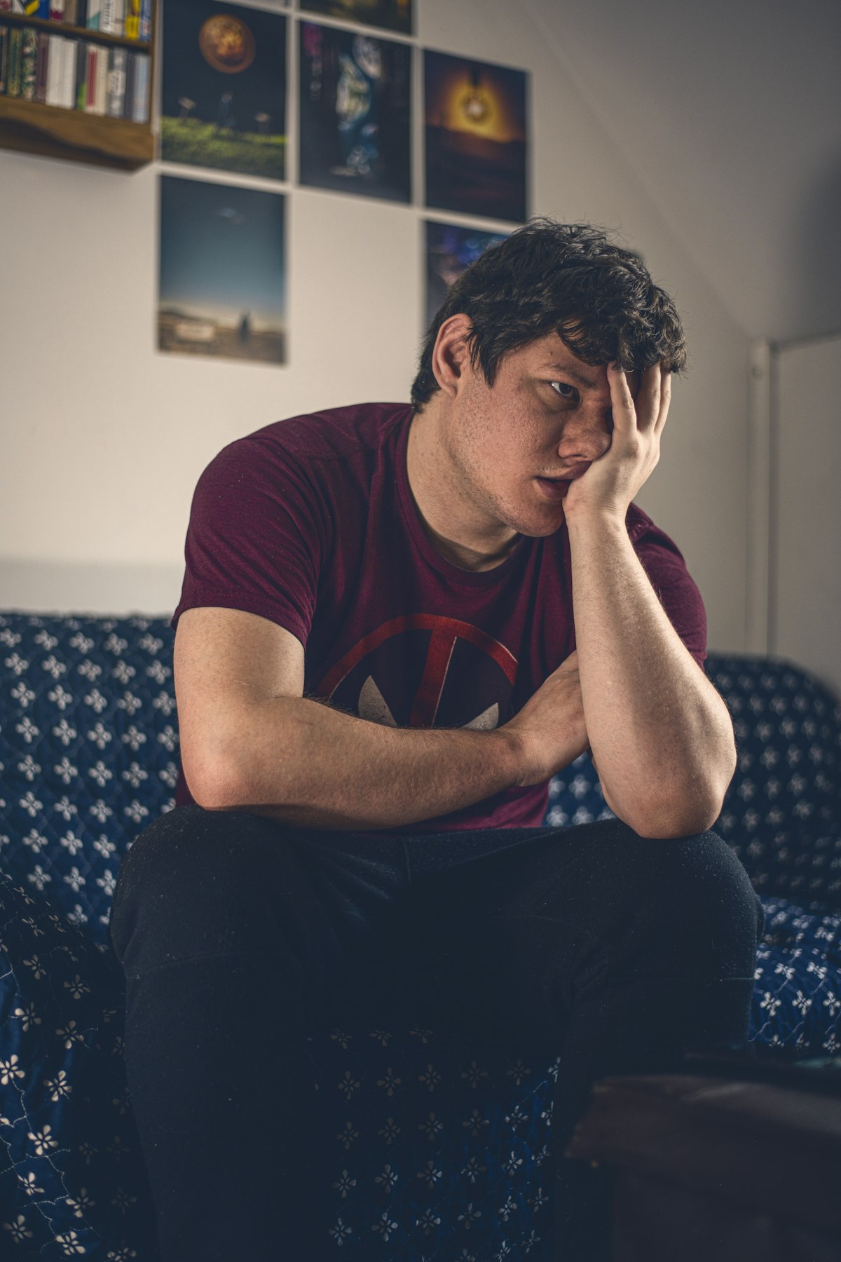 Frustrated man on a couch with his hand on his face, wondering why do I get angry when I'm tired