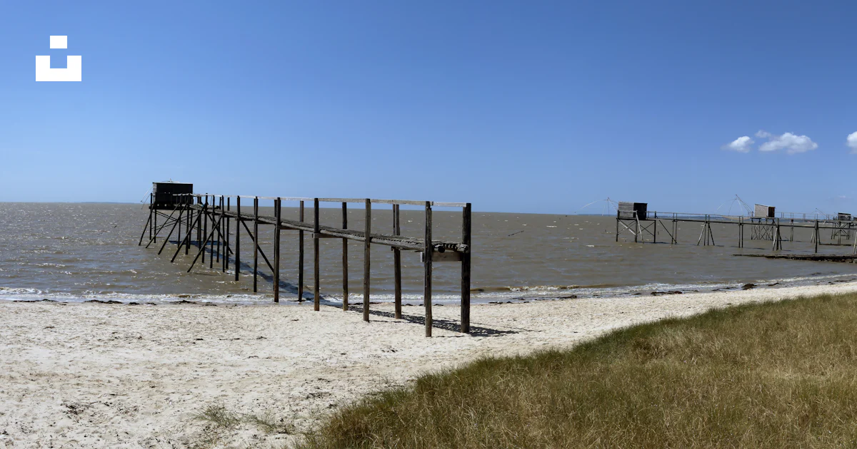 A Wooden Pier Sitting On Top Of A Sandy Beach Photo Free C te a-wooden-pier-sitting-on-top-of-a-sandy-beach-photo-free-c-te