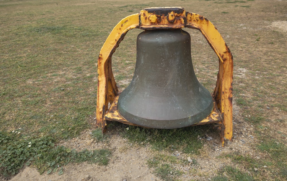 a large metal bell sitting in the middle of a field
