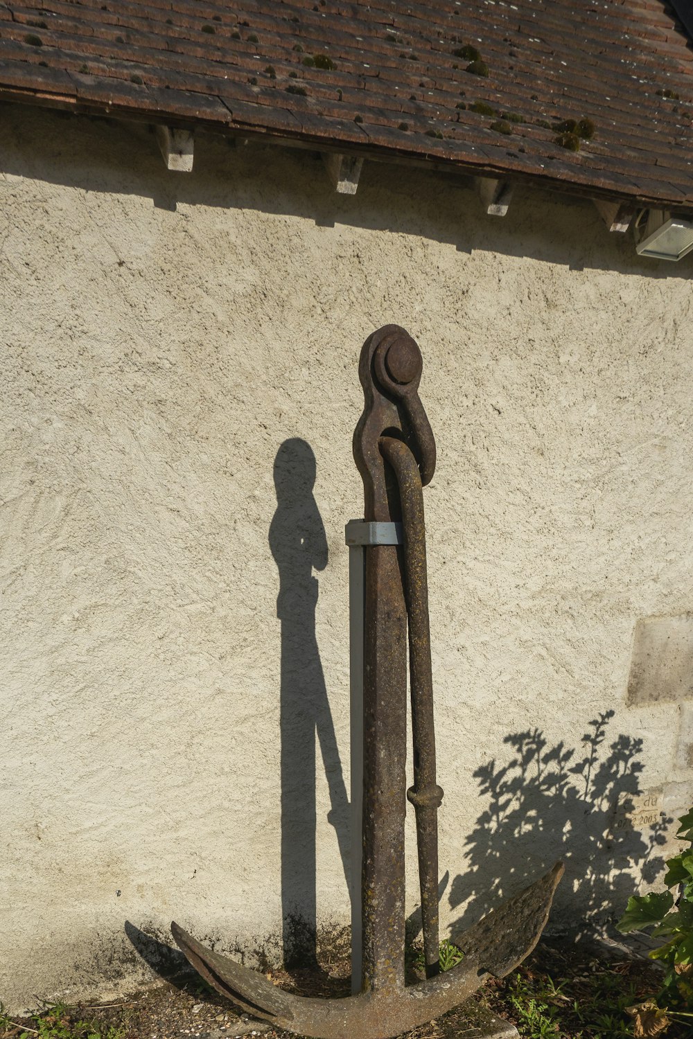 a rusted metal pole next to a white building