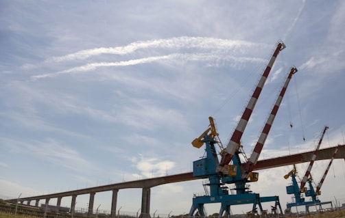 Side view of a box girder segment being positioned by cranes at a large infrastructure project.