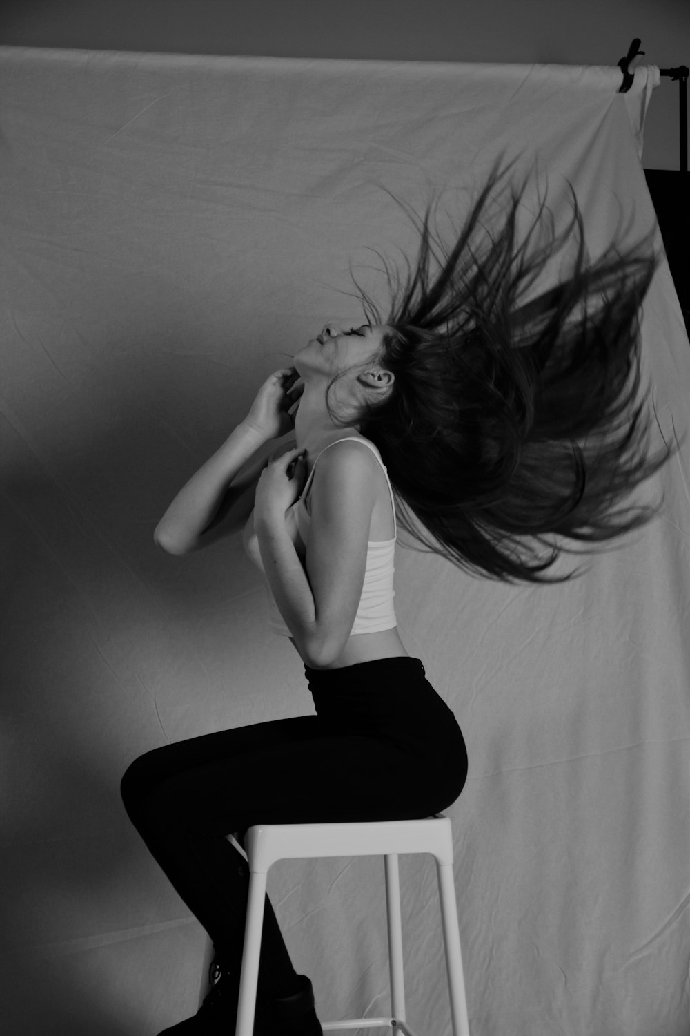 a woman sitting on a stool with her hair blowing in the wind