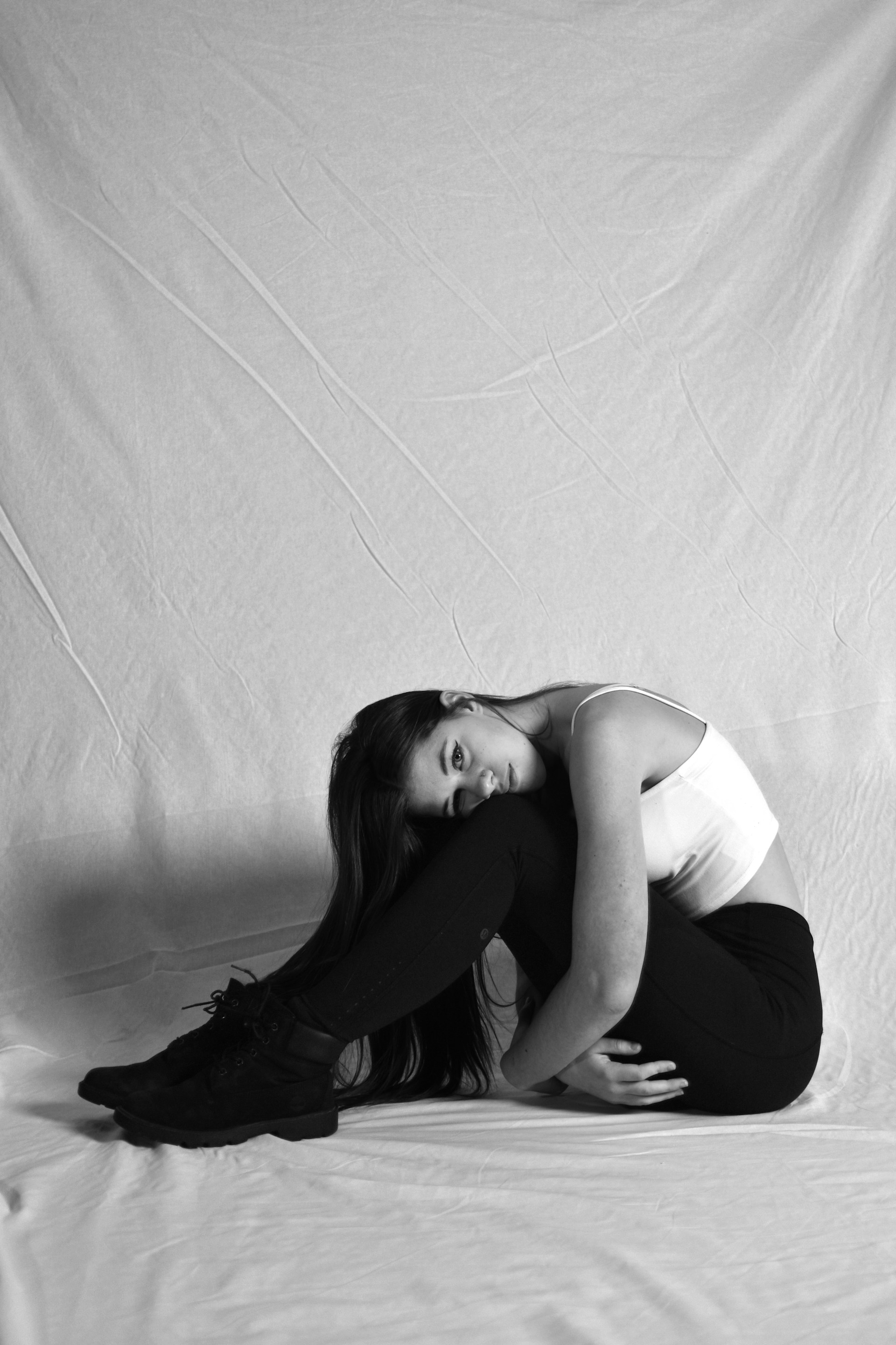 a black and white photo of a woman sitting on a bed