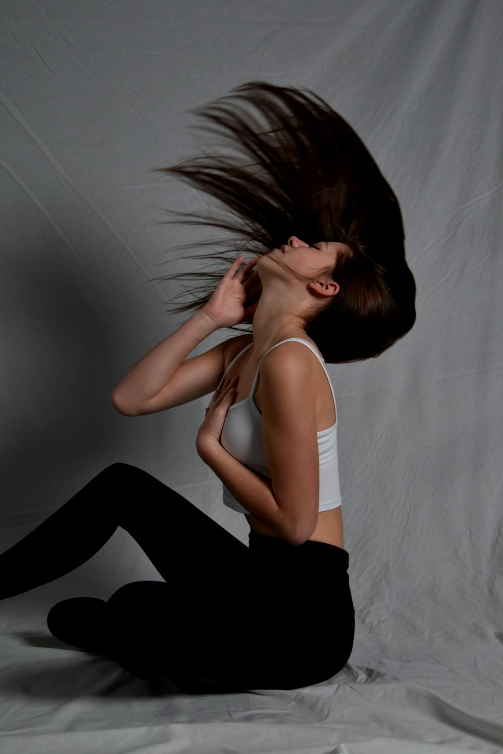 a woman sitting on the floor with her hair blowing in the wind