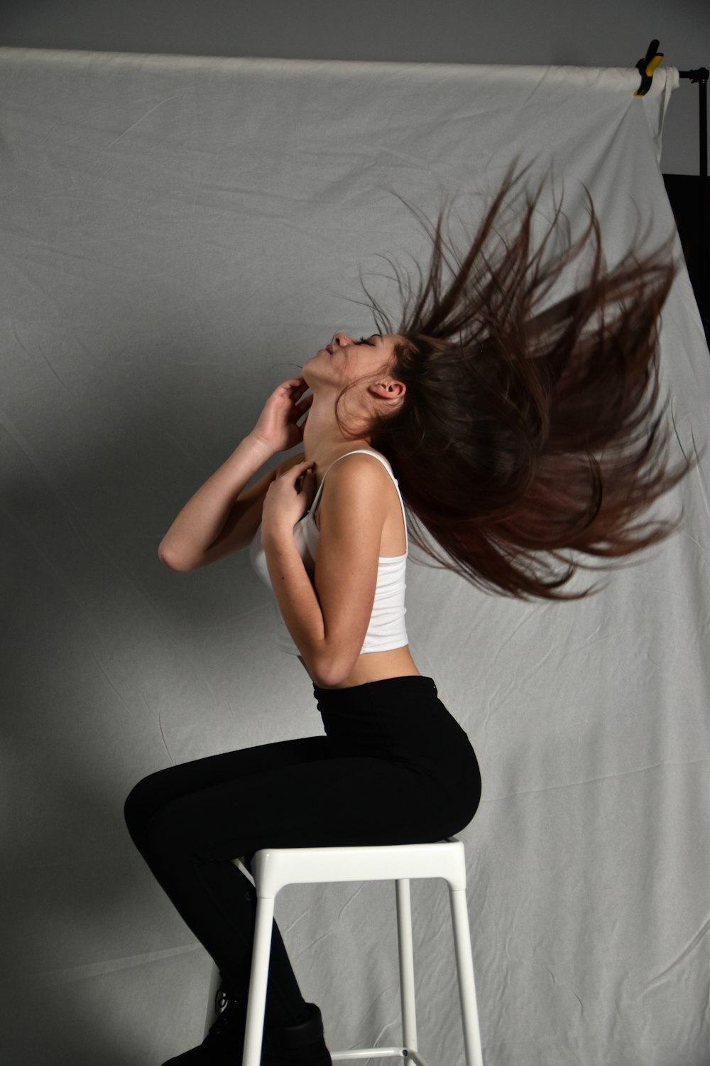 a woman sitting on a stool with her hair in the air