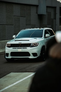a white jeep driving down a street next to a building