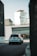 A white SUV is driving down a quiet urban street with a large building in the background featuring signage for 'Storage' and 'Green Box'. The scene has a modern, industrial feel with sleek architecture and muted tones.