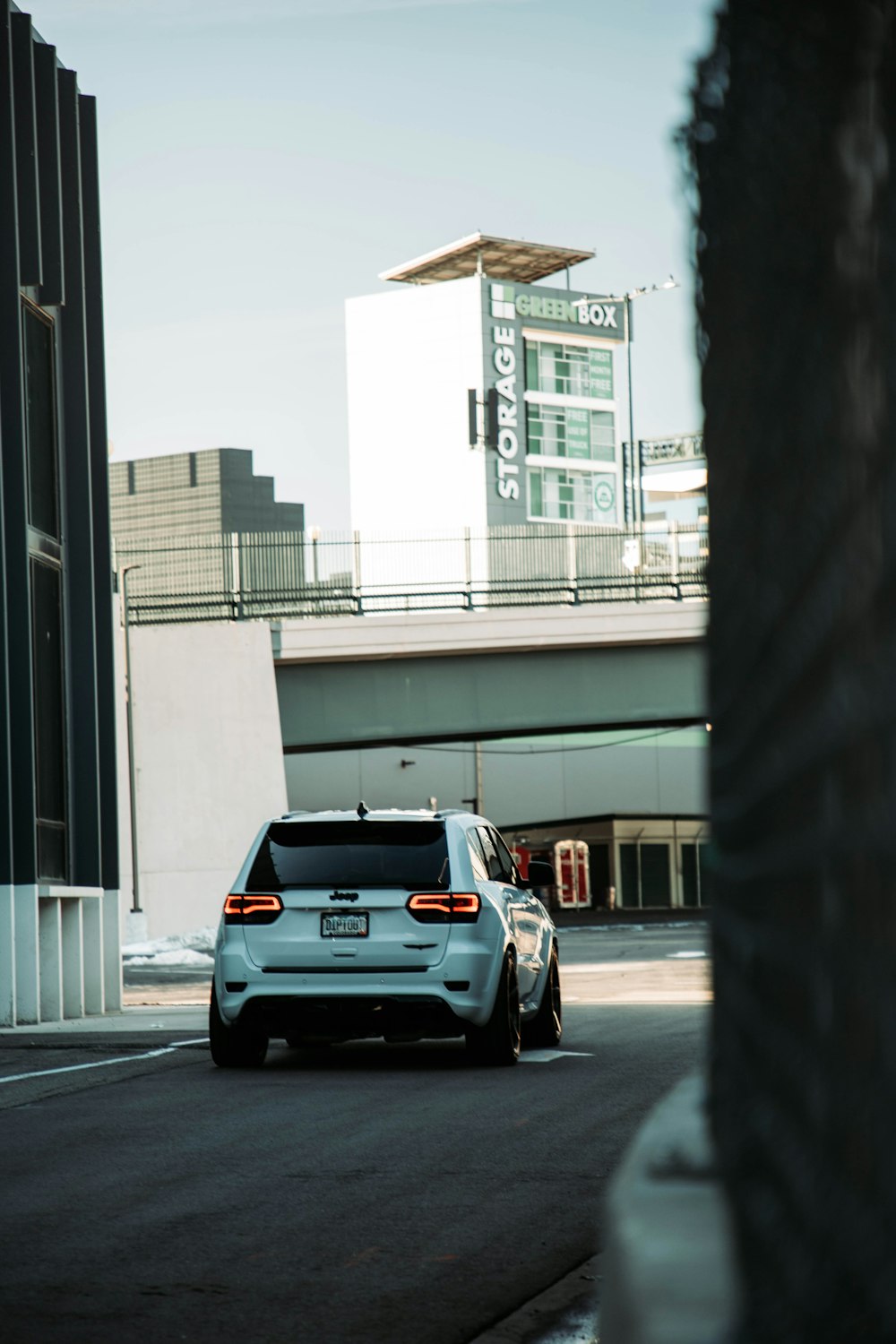 a white car driving down a street next to tall buildings