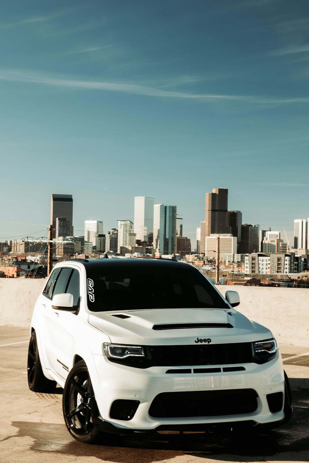 a white jeep parked in front of a city skyline