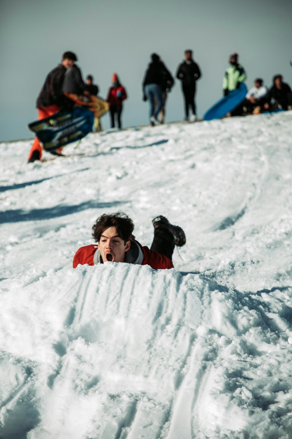 a person laying in the snow in front of a group of people