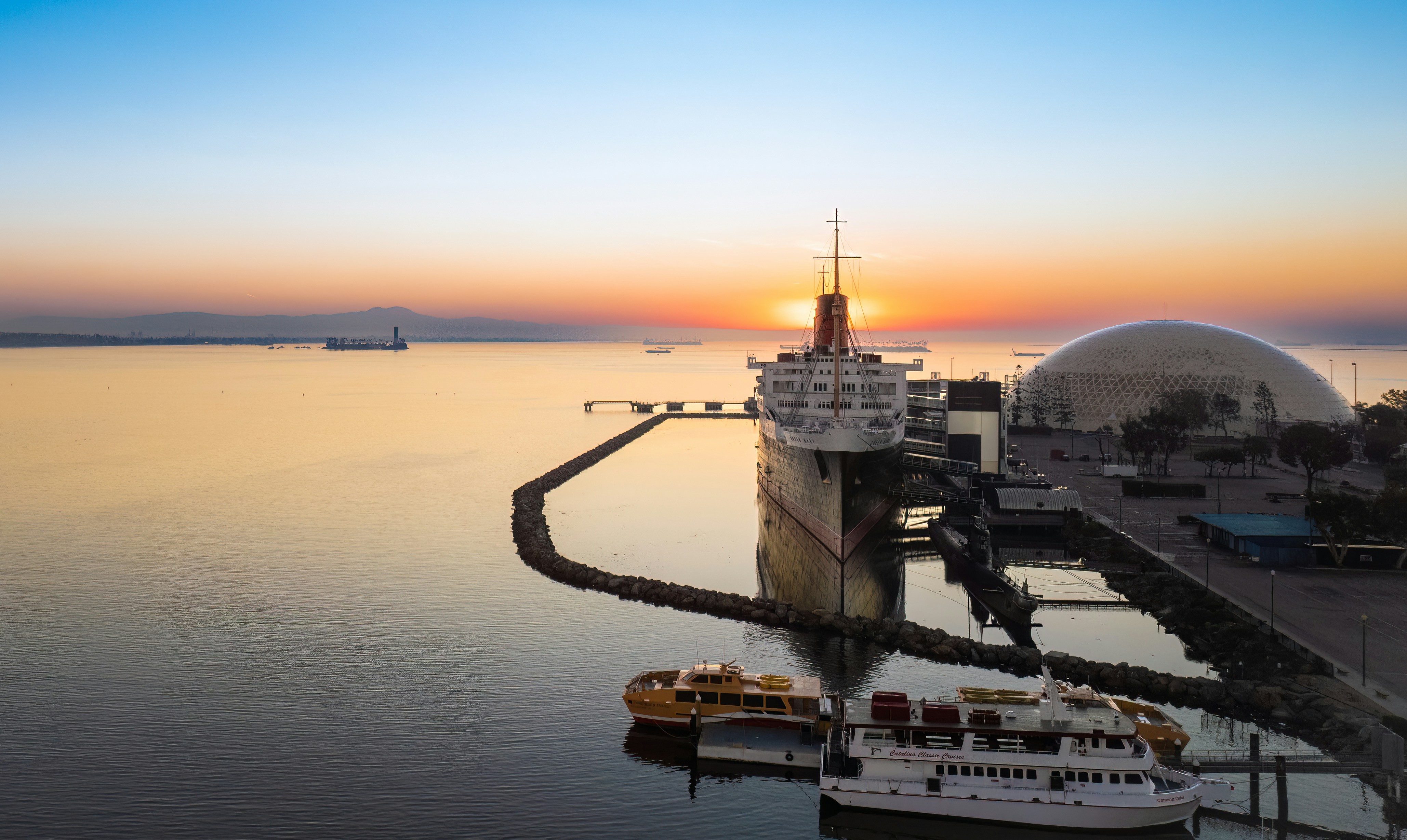 a cruise ship docked in a harbor at sunset